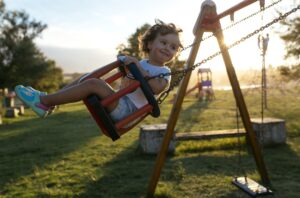 Portrait of happy little girl on a swing at backlight